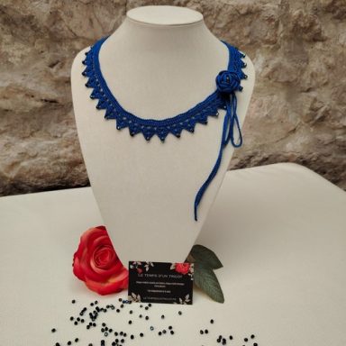 Collier en crochet bleu avec une fleur et un motif en dentelle.